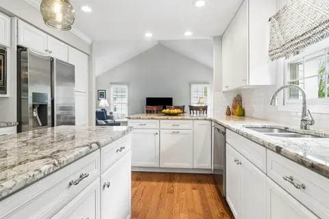a kitchen with granite countertop stainless steel appliances white cabinets and a sink