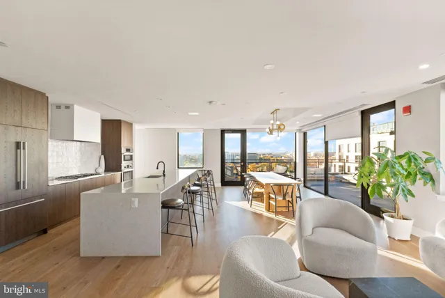 a living room with furniture kitchen view and large windows