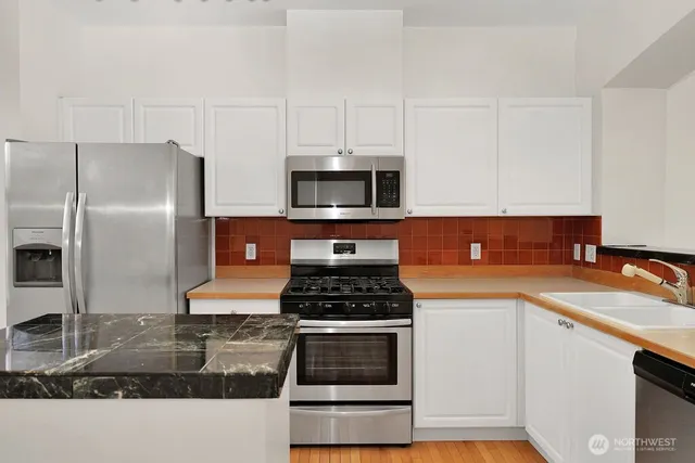 a kitchen with granite countertop a sink stove and refrigerator