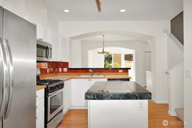 a kitchen with stainless steel appliances granite countertop a refrigerator and a stove