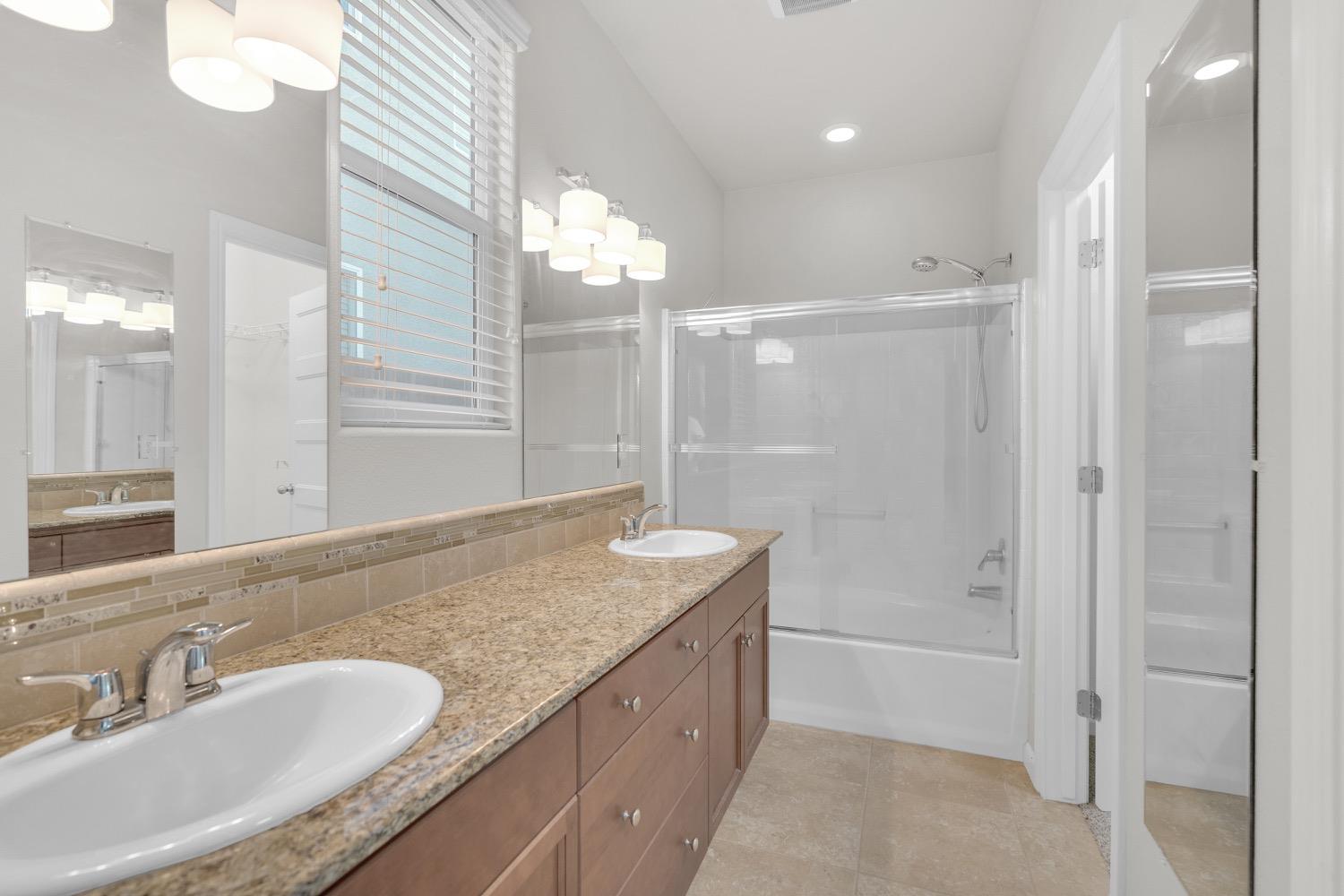 3532 Journey Way Clovis, CA 93619 - Photo 15 of 24 a bathroom with a granite countertop sink a mirror and a bathtub