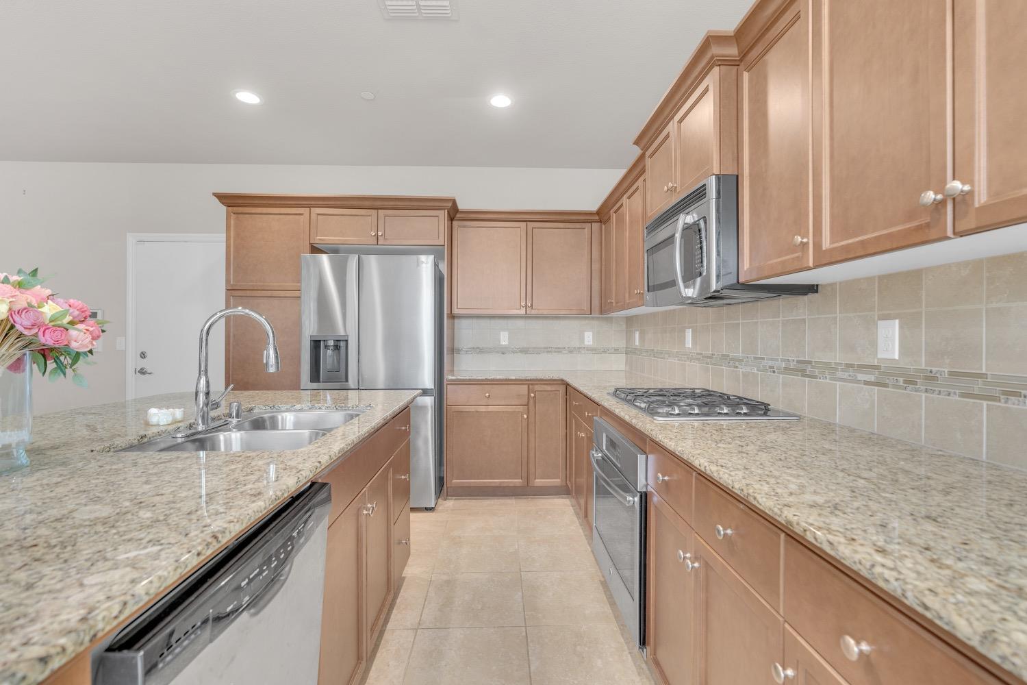 3532 Journey Way Clovis, CA 93619 - Photo 4 of 24 a kitchen with granite countertop a sink stainless steel appliances and cabinets
