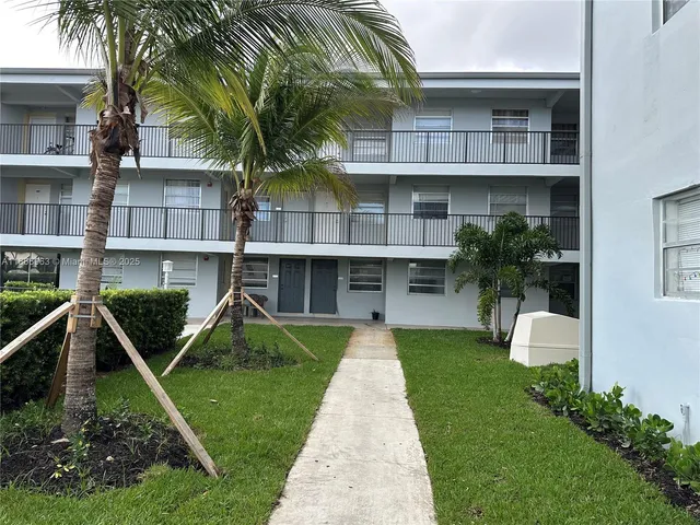 a front view of a house with a yard and potted plants