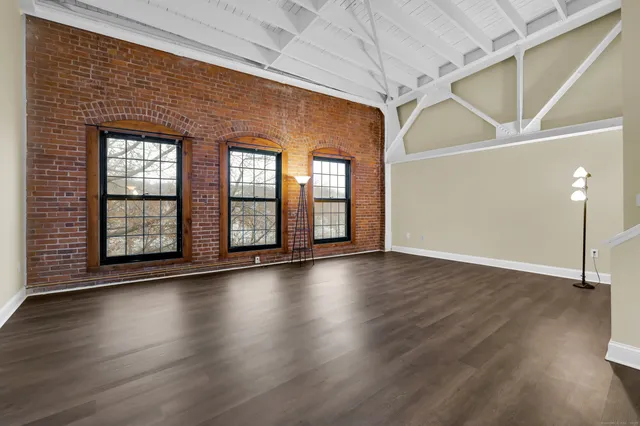 a view of an empty room with wooden floor and windows