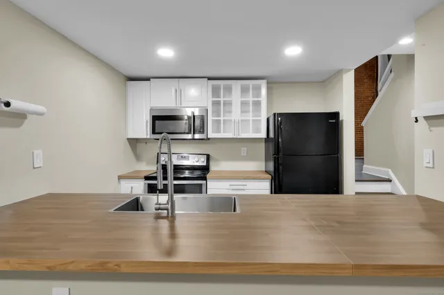 a kitchen with granite countertop a refrigerator and a stove top oven