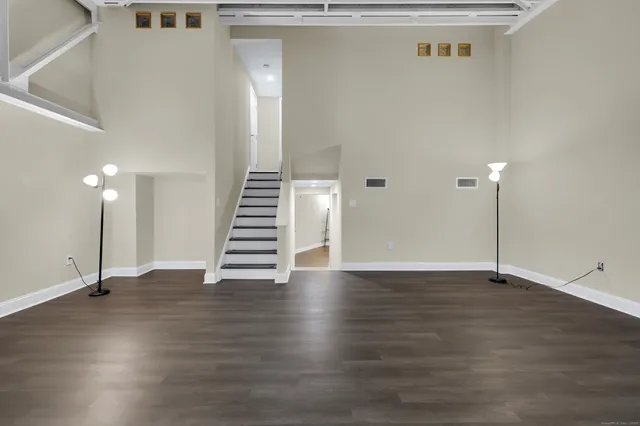 a view of an empty room with wooden floor and stairs