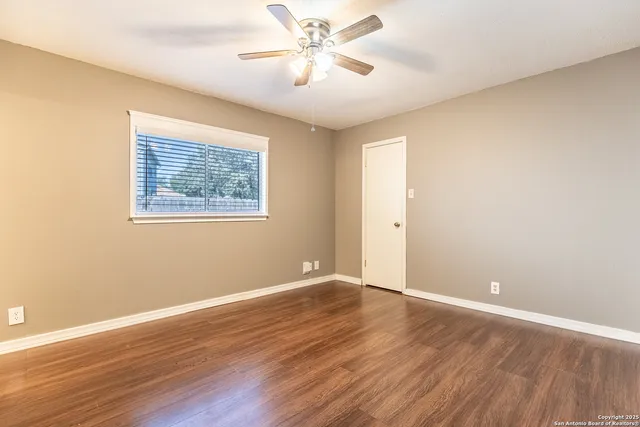 a view of an empty room with window and wooden floor