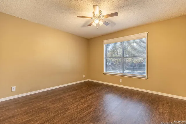 a view of an empty room with a window and wooden floor