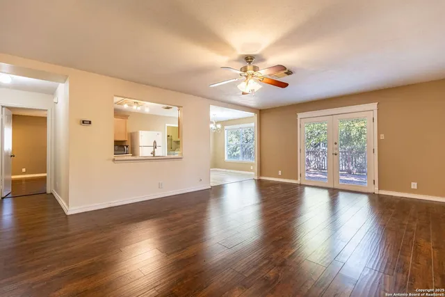 a view of an empty room with window and wooden floor