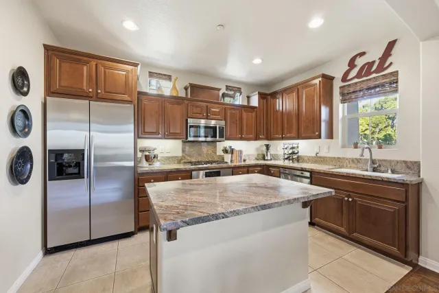 a kitchen with stainless steel appliances granite countertop a refrigerator sink and stove