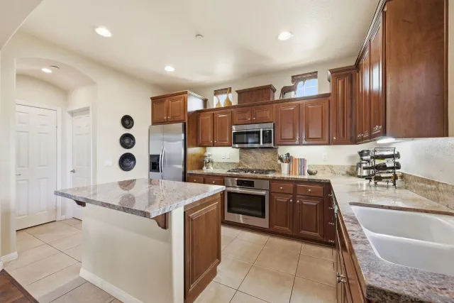 a large kitchen with stainless steel appliances granite countertop a sink dishwasher stove and refrigerator