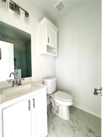 a bathroom with a granite countertop toilet sink and mirror
