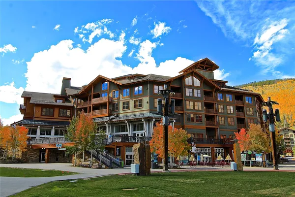 a front view of a building with lot of cars and trees