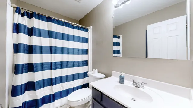 a bathroom with a sink a toilet a mirror and shower curtain