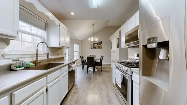 a kitchen with stainless steel appliances a stove a sink a refrigerator and wooden cabinets