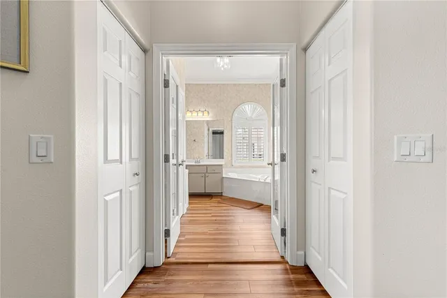 a view of a hallway with wooden floor and a bathroom
