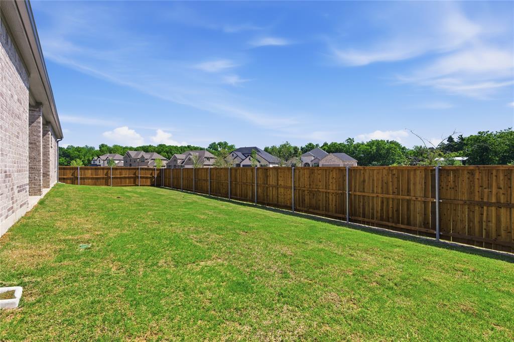713 Anne Road Van Alstyne, TX 75495 - Photo 27 of 29 Expansive green lawn featuring a wood privacy fence and a brick-sided exterior