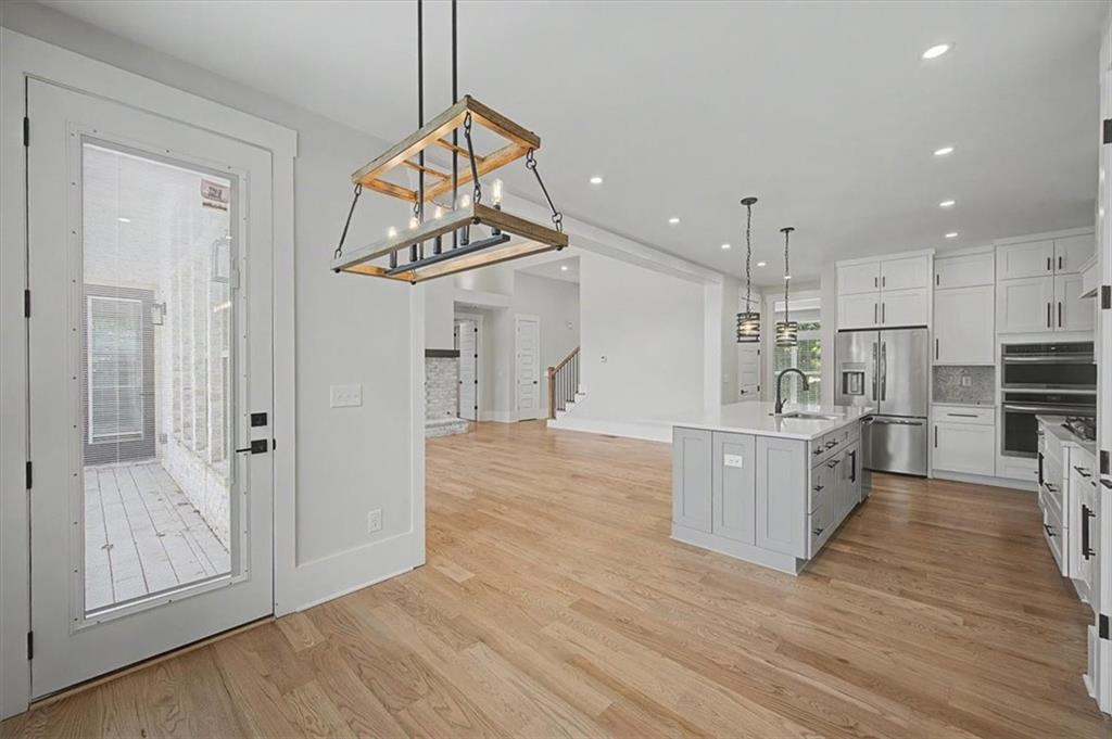 217 Laura Lake Road Marietta, GA 30066 - Photo 22 of 54 a kitchen with stainless steel appliances kitchen island wooden floors and white cabinets