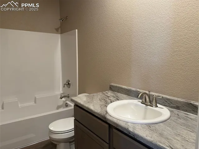 a bathroom with a granite countertop sink toilet and a mirror