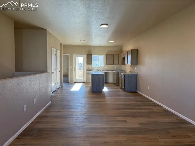 a view of a kitchen with kitchen island wooden floors and stainless steel appliances
