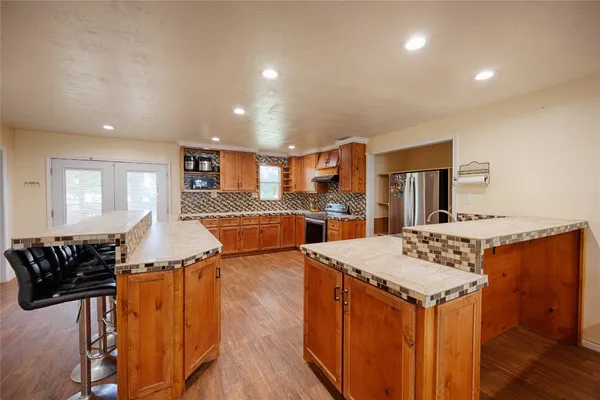 a kitchen with stainless steel appliances granite countertop a stove a sink dishwasher and a refrigerator with wooden floor