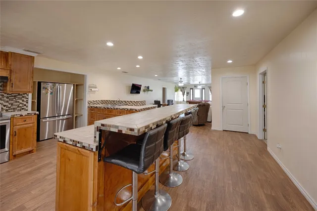 a kitchen with stainless steel appliances kitchen island granite countertop a table chairs in it and wooden floors