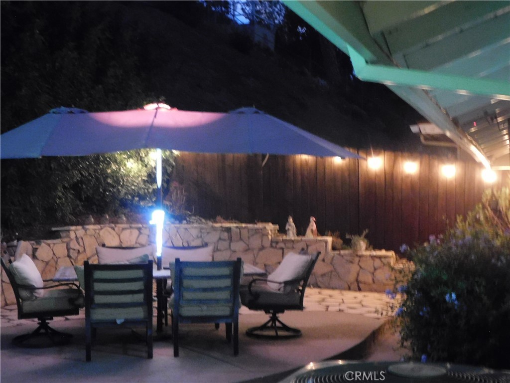 2013 Morning Canyon Road Diamond Bar, CA 91765 - Photo 21 of 26 a view of a patio with table and chairs under an umbrella with a fire pit and wooden fence