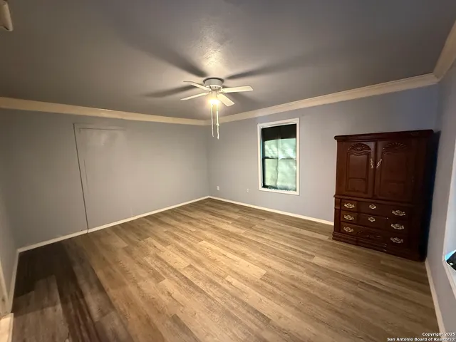 a view of empty room with wooden floor and fan