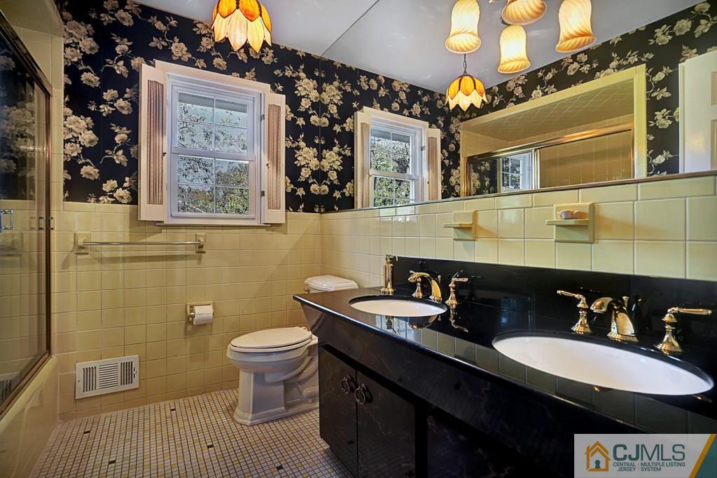 1081 Raritan Road Scotch Plains, NJ 07076 - Photo 18 of 27 a bathroom with a sink a toilet and a mirror