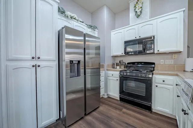 a kitchen with stainless steel appliances granite countertop a refrigerator a stove and a sink with wooden floor