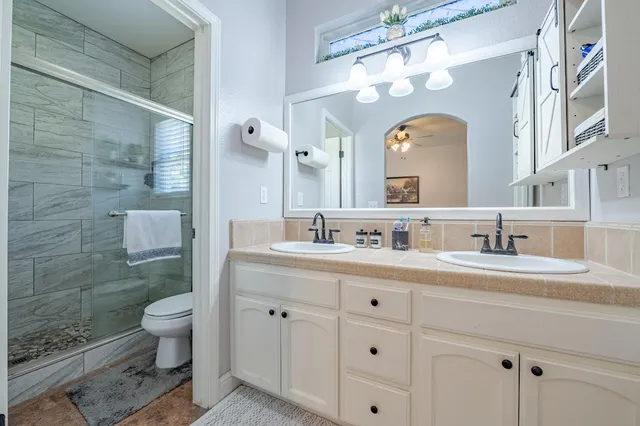 a bathroom with a granite countertop sink a mirror and a toilet