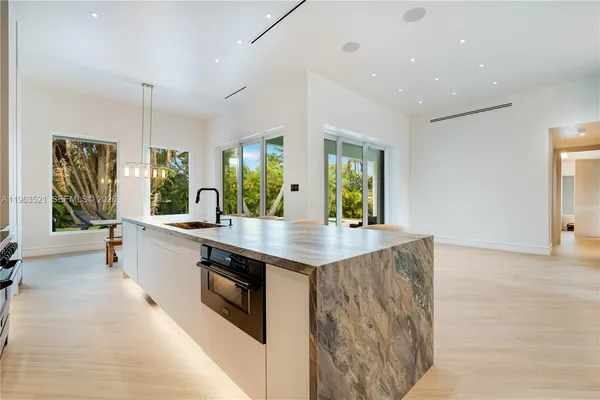 a kitchen with stainless steel appliances kitchen island granite countertop a table and chairs in it
