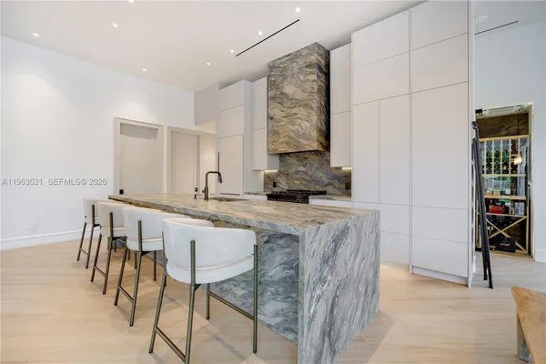 a dining hall with stainless steel appliances granite countertop a stove a refrigerator a sink a dining table and chairs with wooden floor