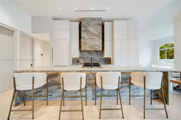 a view of a kitchen with kitchen island a counter top space a sink a refrigerator and a view of living room
