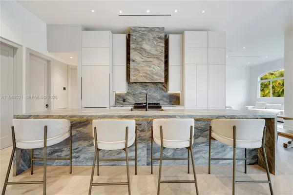 a large kitchen with stainless steel appliances a large counter top a stove a chimney a sink and a refrigerator