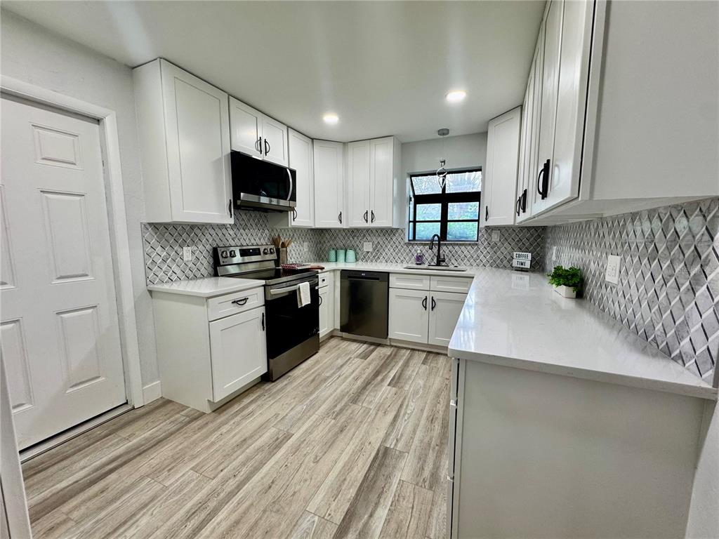 5407 Southwest 82 Terrace Gainesville, FL 32608 - Photo 6 of 31 a kitchen with stainless steel appliances granite countertop a stove top oven a sink dishwasher and a refrigerator with wooden floor