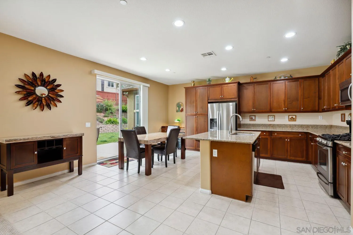 3250 Beven Drive Escondido, CA 92027 - Photo 7 of 34 a kitchen with kitchen island granite countertop a stove a refrigerator a sink a dining table and chairs with wooden floor