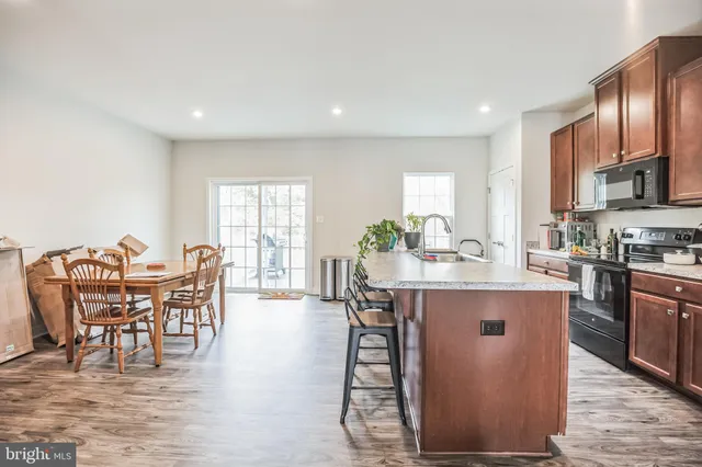 a dining hall with stainless steel appliances granite countertop a kitchen island a table and chairs