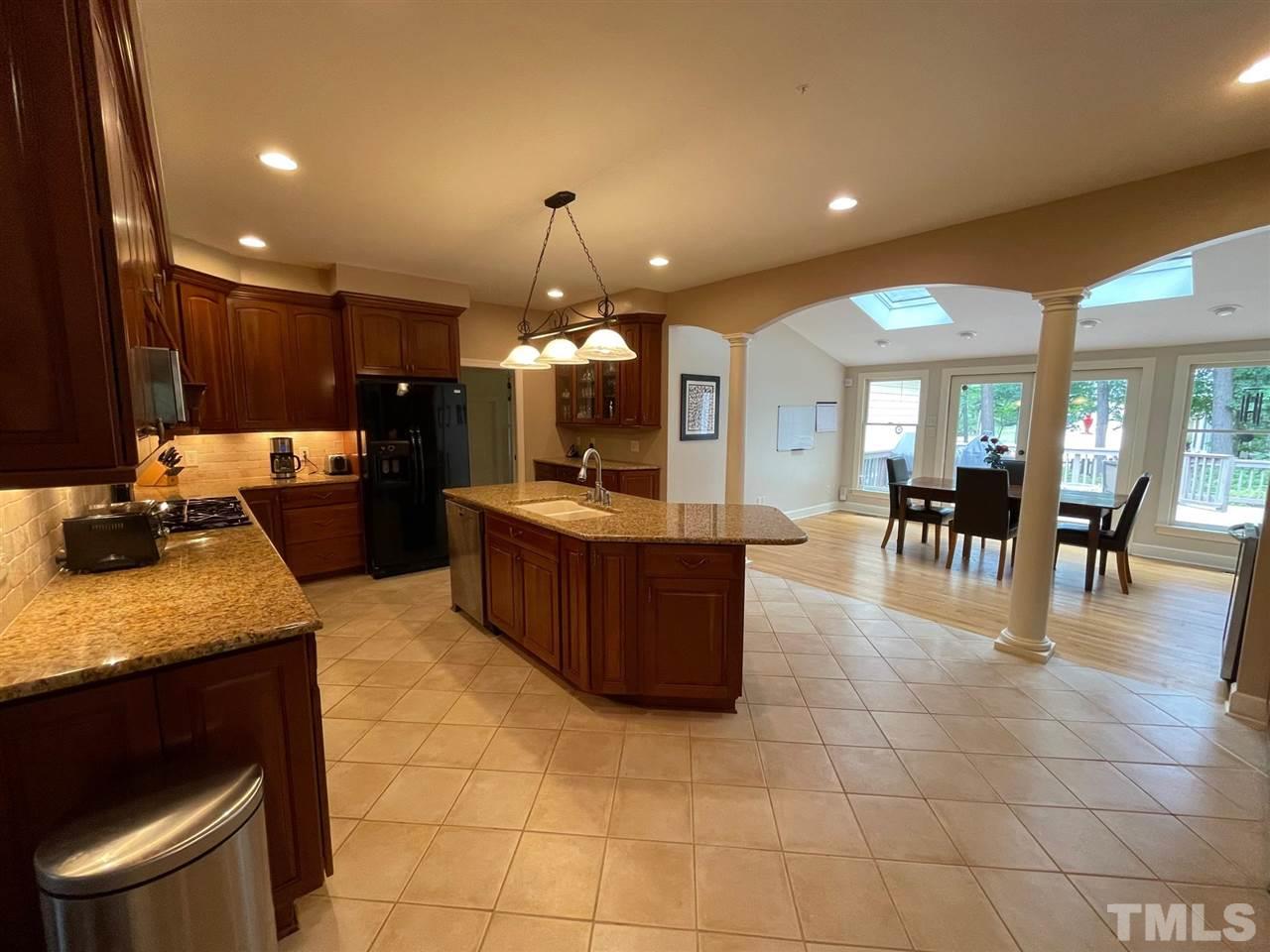 a large kitchen with kitchen island a sink a counter and a view of living room
