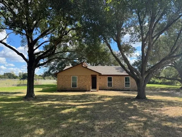 a front view of a house with a garden and tree