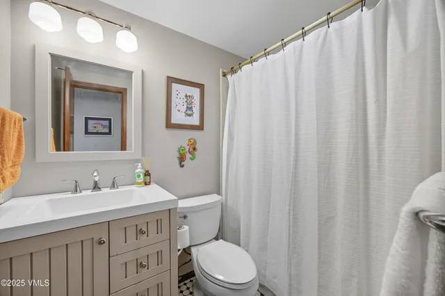 a bathroom with a sink a toilet and shower curtain