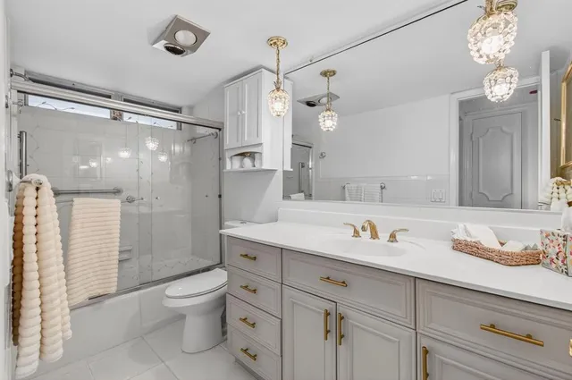 a bathroom with a granite countertop sink a toilet a mirror and shower