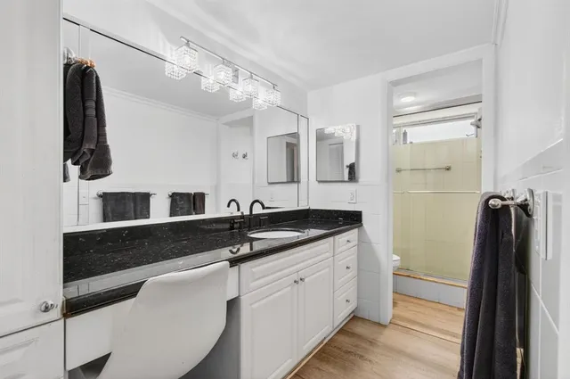 a spacious bathroom with a granite countertop sink a mirror and shower