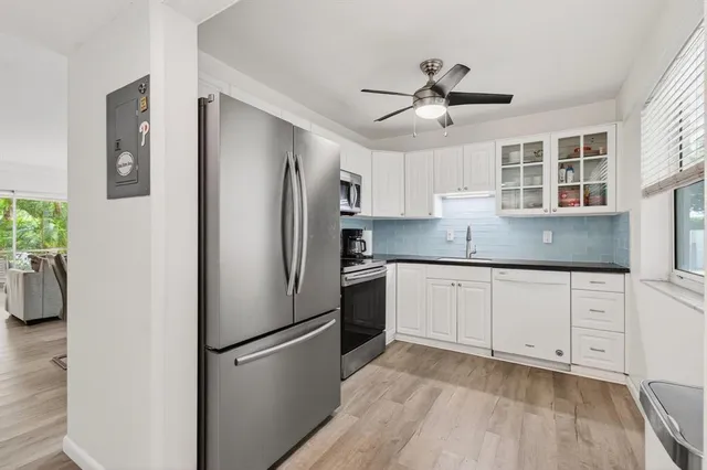 a kitchen with stainless steel appliances granite countertop a refrigerator a stove and white cabinets with wooden floor