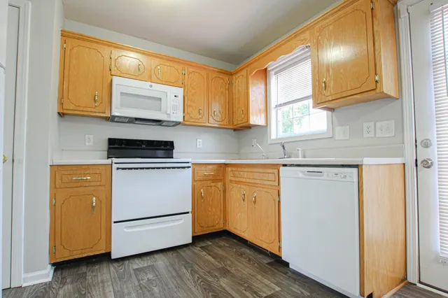 a kitchen with granite countertop wooden floors white cabinets and stainless steel appliances