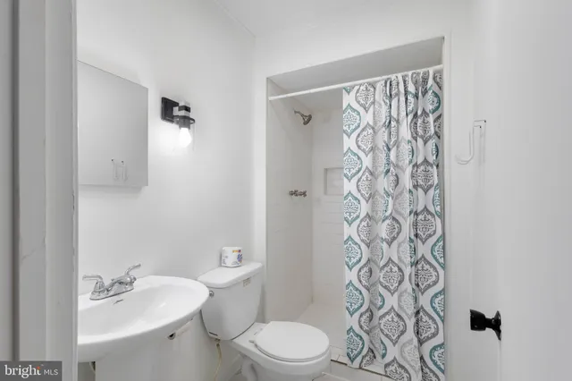 a bathroom with a sink a toilet and shower curtain