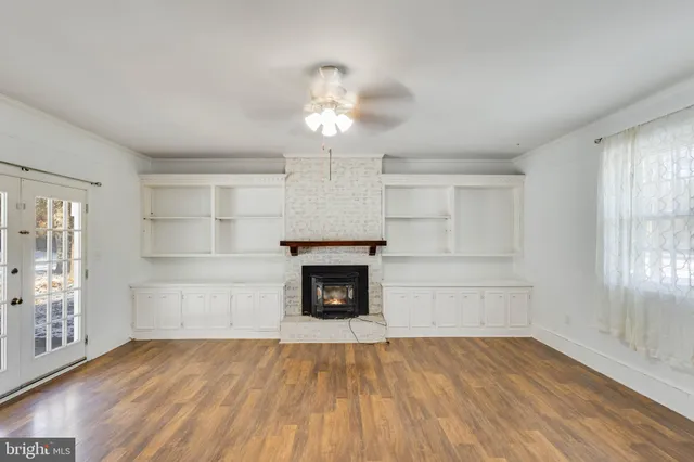 an empty room with windows and fireplace
