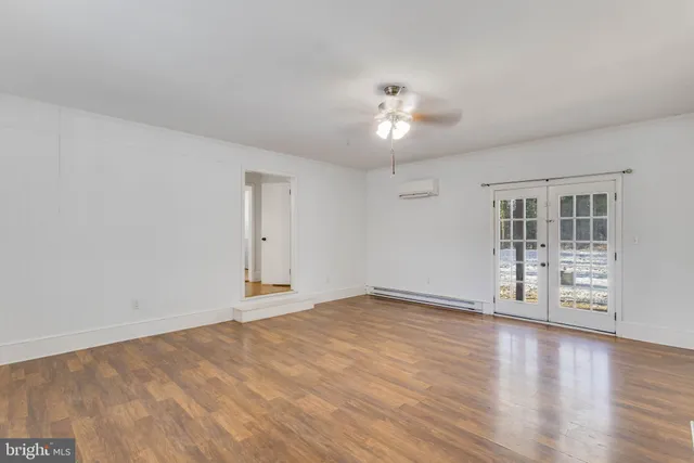 a view of an empty room with a window and wooden floor
