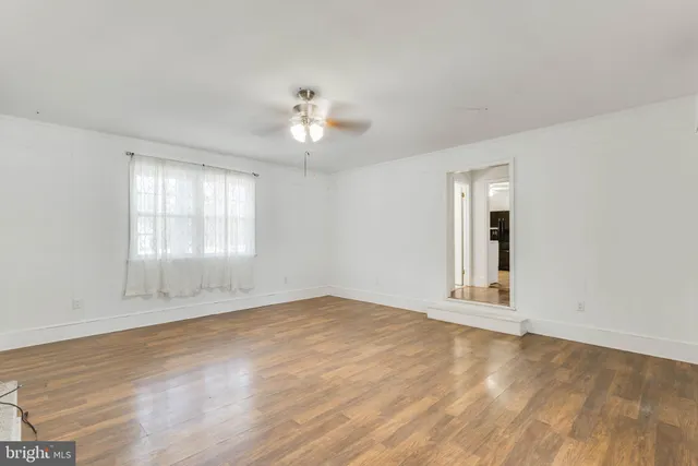 a view of an empty room with a window and wooden floor
