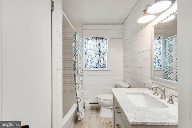 a bathroom with a granite countertop bathtub sink vanity mirror and toilet